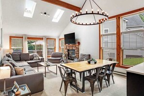 A spacious living room with a fireplace, a dining area, and large windows. - Modern Townhouse with WiFi and Washer/Dryer (Tannersville)