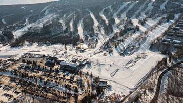 Ein schneebedecktes Skigebiet mit mehreren Gebäuden, Parkplätzen und Skipisten.