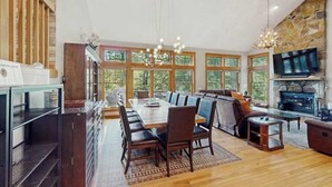 Un espacio habitable amplio con una mesa de comedor grande, asientos cómodos, una chimenea y una televisión.