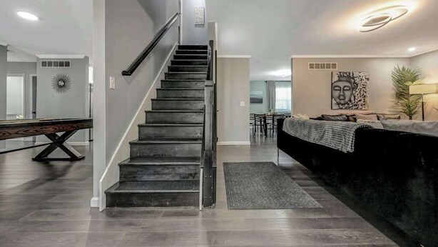 A modern interior with a staircase, a pool table, a sofa, and a Buddha painting. - Spacious House with Hot Tub & Game Room (Long Pond)