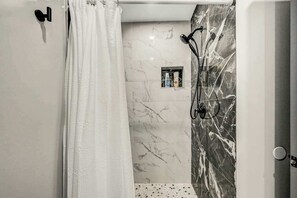 A modern bathroom with a shower, marble walls, and a towel rack. - Long Pond Home with Hot Tub, Billiards & Poker (Long Pond)