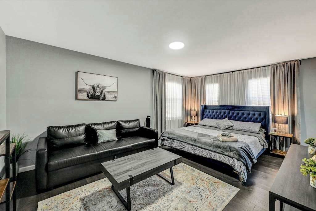 A modern bedroom with a bed, a sofa, a coffee table, and a painting on the wall.