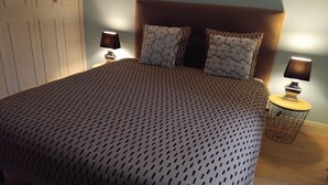 Une chambre à coucher avec un grand lit, deux lampes de chevet et une petite table ronde avec une lampe.