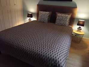 Une chambre Ă coucher avec un grand lit, deux lampes de chevet et une petite table ronde avec une lampe.