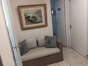 A room with a sofa, a framed painting, a door labeled 'CHAMBRE,' and a tiled floor.