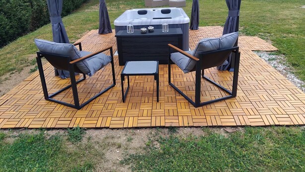 Un belvédère avec un jacuzzi, deux chaises et une table, le tout installé sur une terrasse en bois.