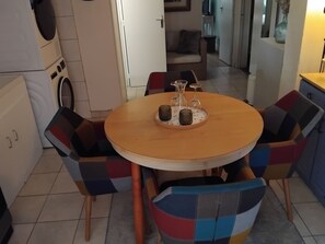 A round wooden table with a central candle holder, surrounded by colorful chairs.