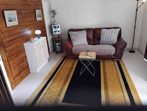 A living room with a brown leather sofa, a small wooden coffee table, a white cabinet, and a patterned rug.