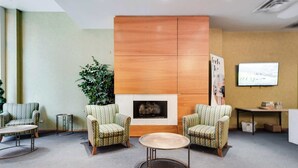 A lobby with two armchairs, a round table, a fireplace, a plant, and a television screen. - Downtown Chicago Stay with Free In & Out Parking-2 (Chicago)
