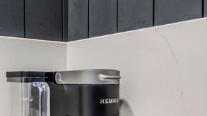 Una cafetera Keurig negra sobre una encimera blanca con una jarra de vidrio transparente.