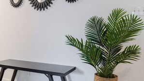 Una habitación con una mesa de madera oscura, tres espejos fijados a la pared y una planta en maceta.