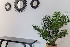 Una habitación con una mesa de madera oscura, tres espejos fijados a la pared y una planta en maceta.