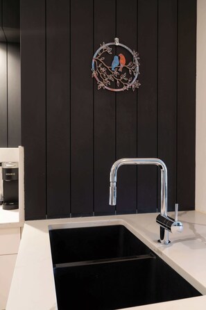 Een keuken met een moderne kraan, een koffieapparaat en een decoratief wandobject.