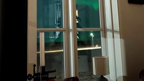 Una habitación con un ventanal grande, una lámpara y un cuadro en la pared.