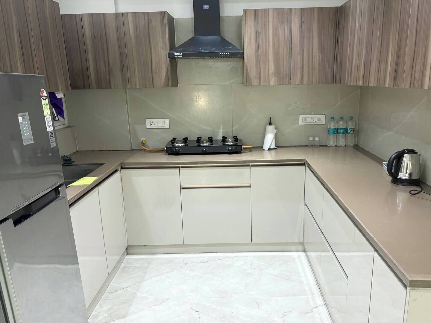 Een moderne keuken met een roestvrijstalen koelkast, een gasfornuis en houten kastjes.