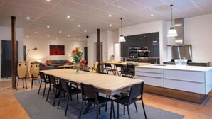 A modern kitchen with a central island, dining area with chairs, and a sofa.
