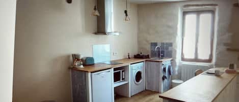 Une petite cuisine équipée d’un lave-linge, d’un évier et d’une fenêtre.