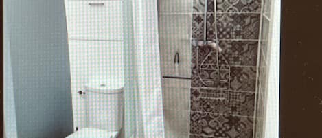 A bathroom with a toilet, a shower enclosure, and a patterned wall.