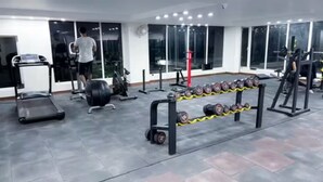 Ett gym med träningsutrustning, ett löpband och en ställning för vikter.