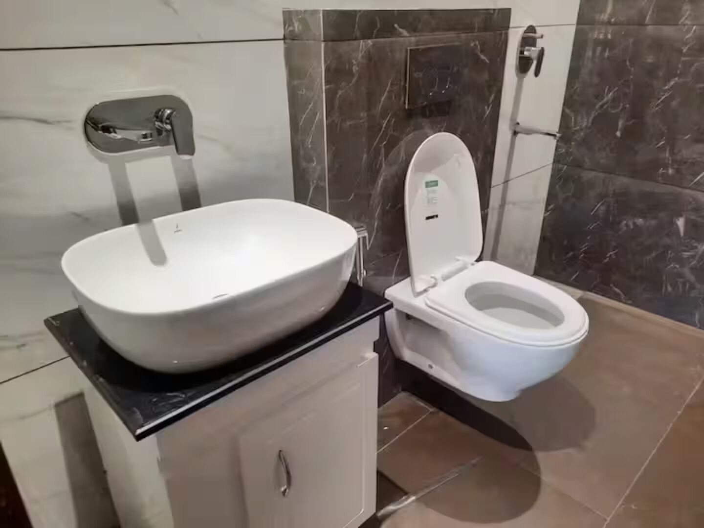 Een badkamer met een wit wastafel, toilet en muren betegeld met marmer.