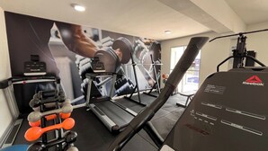 Et træningscenter med løbebånd, håndvægte og en motionscykel fra Reebok.