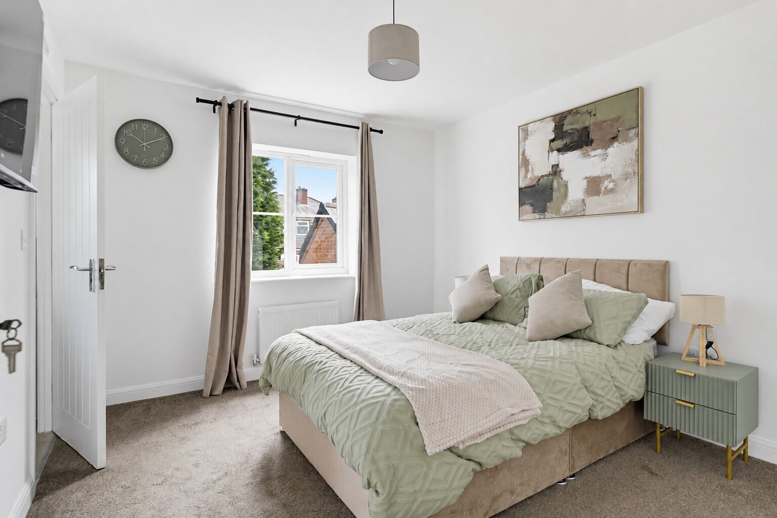 A bedroom with a bed, a clock, a window with curtains, a painting, and a bedside table with a lamp.