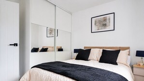 Een slaapkamer met een bed, nachtkastjes, een kledingkast, een spiegel en een lijst aan de muur.