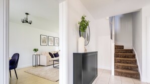 Een modern interieur met een trap, een zithoek, een radiator en een kamerplant.