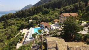 A resort with a swimming pool, multiple buildings, and a mountainous backdrop. - Brentanos Apartments - View of Paradise (Corfu)