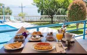 A breakfast table with croissants, a plate of toast, an omelette, and a glass of orange juice. - Brentanos Apartments - View of Paradise (Corfu)