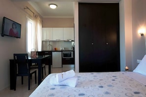 A hotel room with a bed, a small table, and a kitchenette. - Brentanos Apartments - View of Paradise (Corfu)
