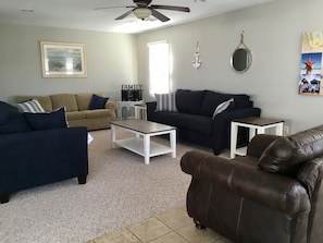 A living room with a beige sofa, a dark blue sofa, a brown leather armchair, a white coffee table, and a ceiling fan. - 3-bedroom house w/ Beach View and parking (Bradley Beach)
