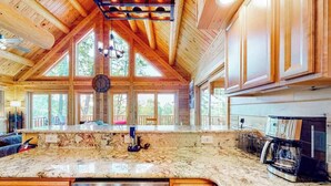A spacious kitchen with a large island, wooden cabinetry, and a coffee machine. - Deep Creek Mountain Retreat (McHenry)