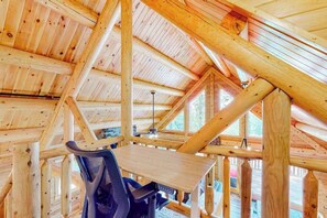 A wooden interior with a high ceiling, visible beams, and a table with a chair. - Deep Creek Mountain Retreat (McHenry)