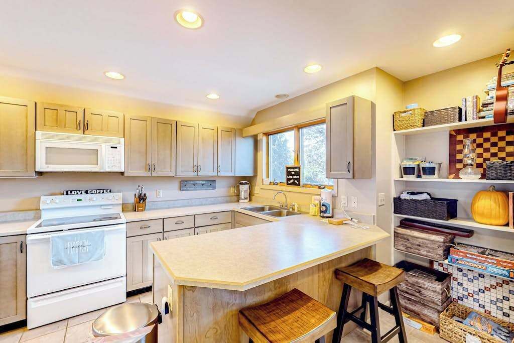 A modern kitchen with a central island, white cabinetry, and a microwave.