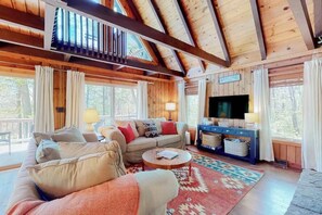A cozy cabin interior with a sofa, a television, and a wooden ceiling.