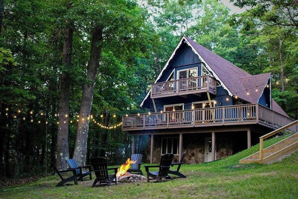A cabin with a balcony, outdoor seating, and a fire pit.