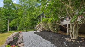 A pathway leading to a building surrounded by trees and a garden with pebbles and rocks. - Poconos Family Retreat | 5 Acres | Sleeps 15 (Barrett Township)