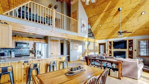 A spacious kitchen with a dining area, a living room with a fireplace, and a loft bedroom with a balcony. - 5BR - Chalet - Hot Tub (McHenry)