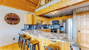 A kitchen with wooden cabinets, a granite countertop, and a bar stool area.