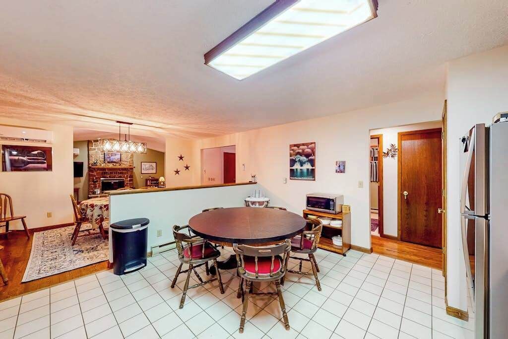 Ein Essbereich mit rundem Tisch und Stühlen, eine Küche im Hintergrund und ein Kühlschrank auf der rechten Seite.