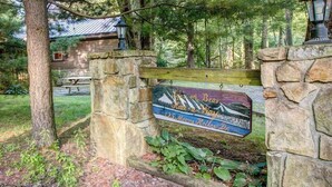 A stone wall with a wooden sign indicating a location. - 3BR - Cozy Cabin - Hot Tub (McHenry)
