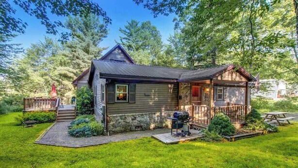 A cabin with a porch, a grill, and a deck. - 3BR - Cozy Cabin - Hot Tub (McHenry)