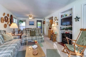 Ein gemütliches Wohnzimmer mit einem Karomuster-Sofa, einem Holztisch, einem Kamin und einem Fernseher.