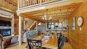 A wooden interior with a dining area, fireplace, kitchen, and staircase. - Rustic 4BR Cabin - HOT TUB - McHenry (McHenry)