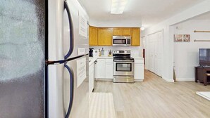 Une cuisine moderne avec des armoires blanches, un four en acier inoxydable, un four à micro-ondes et un réfrigérateur.