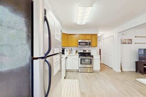A modern kitchen with white cabinets, a stainless steel oven, a microwave, and a refrigerator. - 3BR - Wooded Retreat - Fire Pit (Oakland)