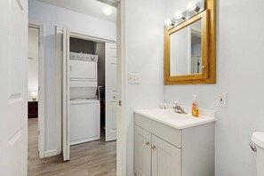 Un bagno con lavandino, specchio e WC bianchi.