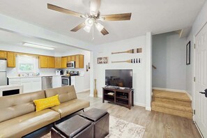 Un soggiorno moderno con divano, televisore e ventilatore a soffitto.