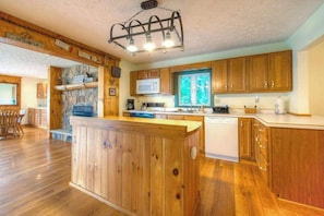 Una cocina con armarios de madera, una isla central, microondas y lavavajillas.